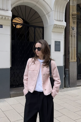 a lady in a pink tweed cololarless jacket and a pair of black pants